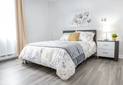 Bedroom with a pale bedspread, bedside table and a window