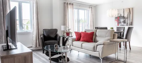 Sitting area with armchairs, a sofa and a television beside windows