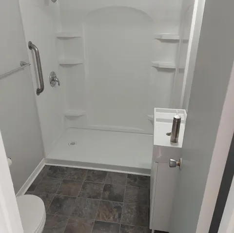 Bathroom with a shower enclosure, grab bar and tiled floor