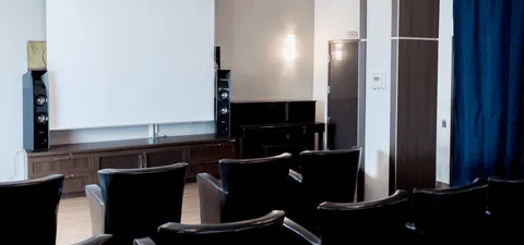 Screening room with dark chairs facing a large blank screen
