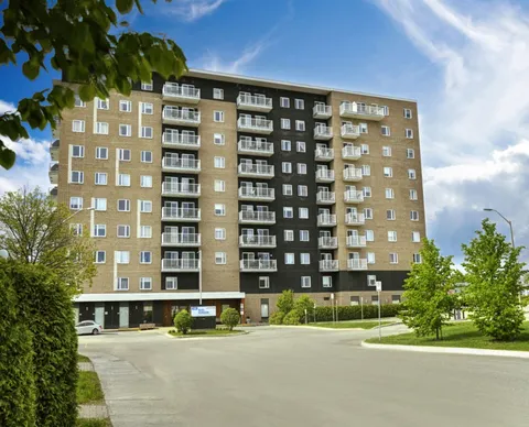 Multi-storey residence with balconies beside a landscaped driveway