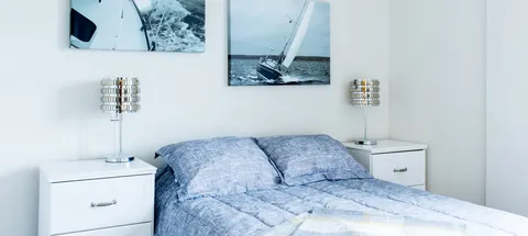 Bedroom with blue bedding and sailboat pictures above the bed