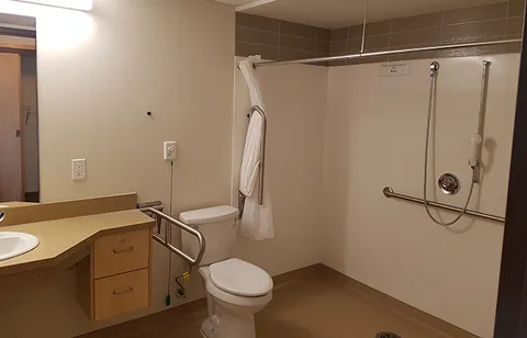 Bathroom with a sink, toilet, walk-in shower and support rails