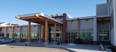 Building with a covered entrance, benches, a bicycle and patches of snow