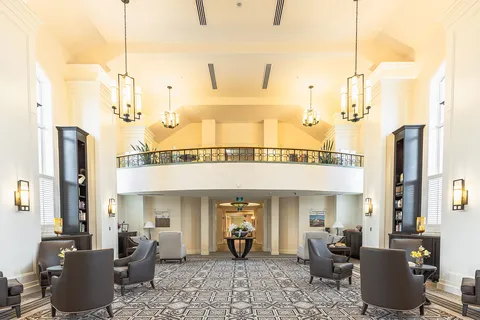 Two-storey lounge with armchairs, chandeliers and a balcony railing