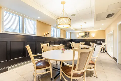 Room with round dining tables, wooden chairs, pendant lights and dark wall panels