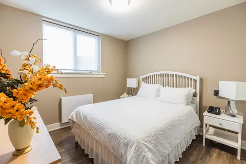 Bedroom with a white bed, bedside tables, lamps and a window