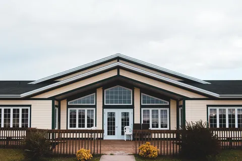 Building facade with tall windows and a timber deck.