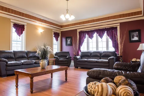 Lounge with leather sofas, coffee table and curtained windows.