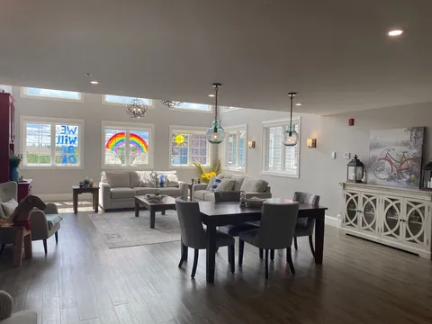Room with sofas, a dark table and chairs, large windows and a sideboard with bicycle artwork
