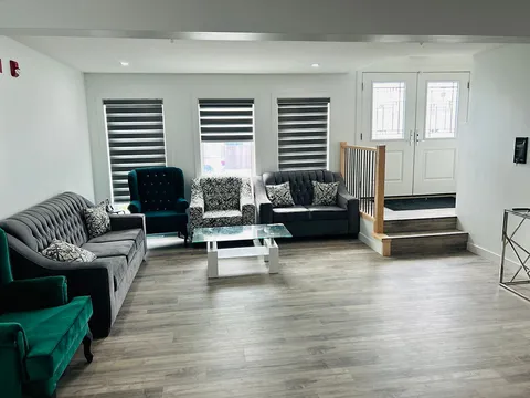 Sitting room with grey sofas, green armchairs and a glass coffee table.