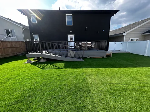 Rear of the residence with a raised deck, ramp, lawn and boundary fences.