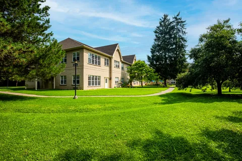 Side of the residence beside a lawn and trees.