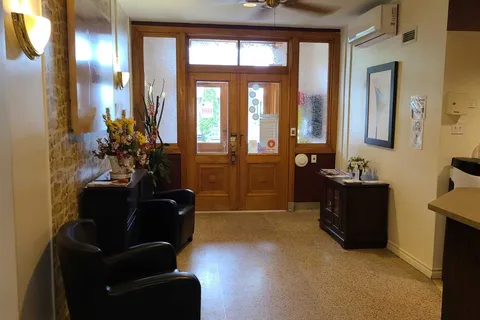Entrance hall with wooden doors, black armchairs and flower arrangements
