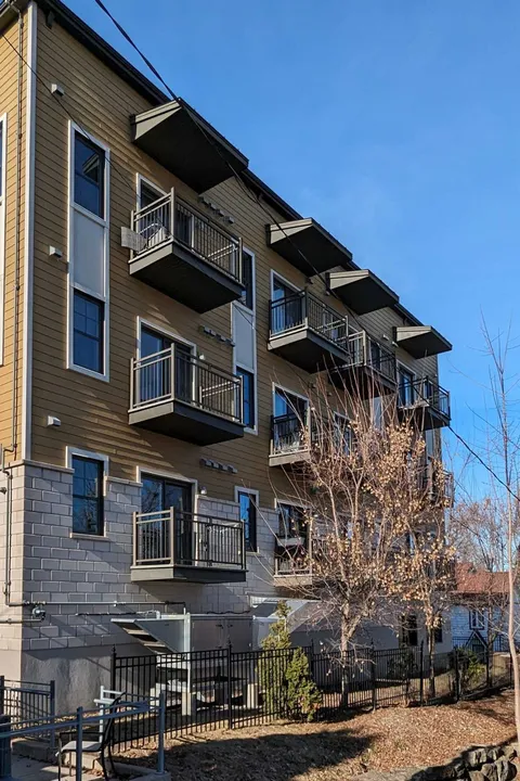 Building with balconies, a covered entrance and flower beds