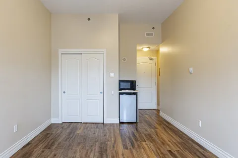 Unfurnished room with a closet, wood flooring and a refrigerator