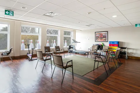 Activity room with chairs, exercise equipment and large windows