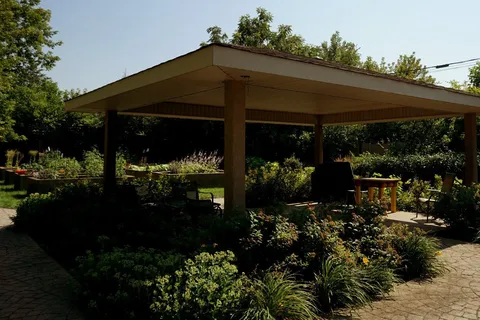 Covered patio surrounded by shrubs and raised garden beds