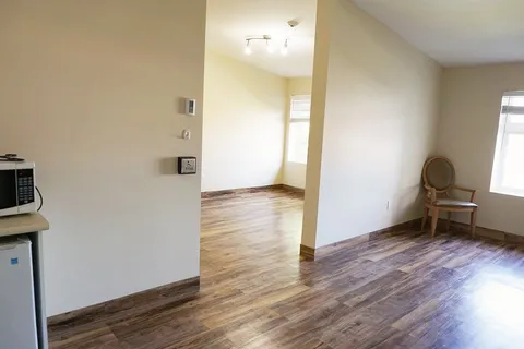 Unfurnished rooms with wood flooring, a chair and a refrigerator