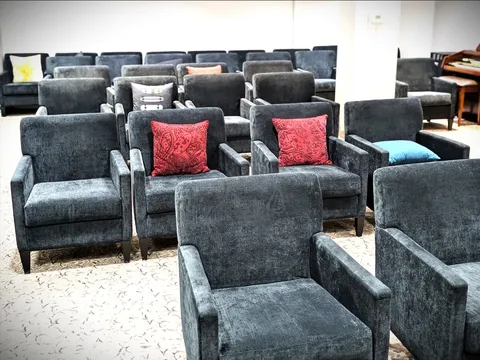 Rows of dark upholstered armchairs in a room with a piano