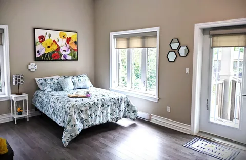 Bedroom with a patterned bedspread, windows and a glazed balcony door