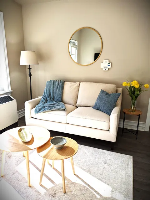 Sofa and small round tables beside a lamp and round wall mirror
