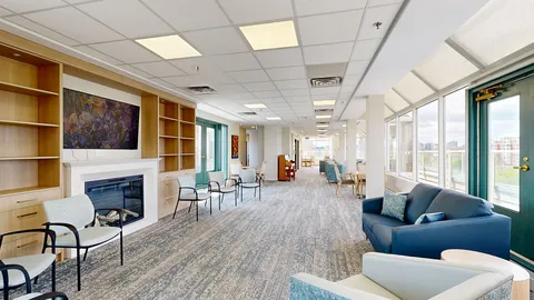 Lounge with blue sofas, armchairs, bookshelves and a fireplace.