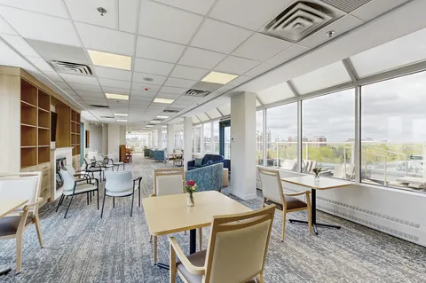 Lounge and dining area with wraparound windows and armchairs.