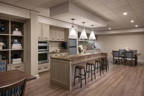 Community kitchen with an island, stools, cabinets and a dining table.
