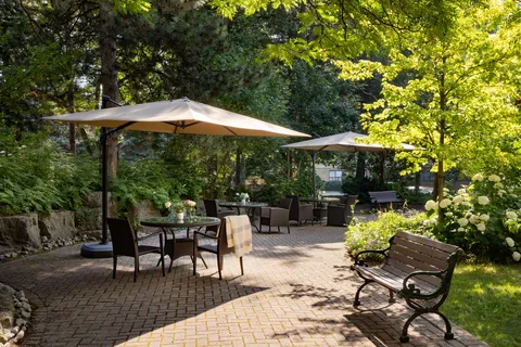 Paved garden patio with umbrella tables, chairs and benches.
