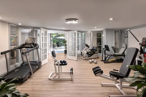 Fitness room with exercise machines and glass doors.