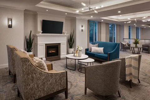 Lounge with upholstered chairs, a fireplace and television.