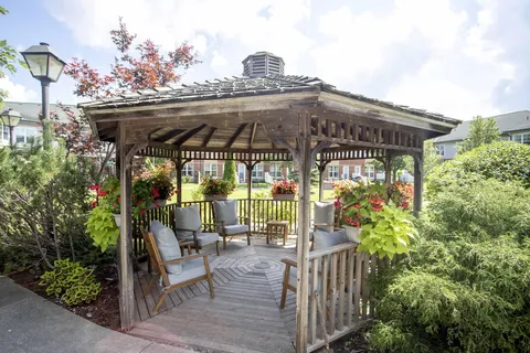 Wooden gazebo with chairs and hanging flower baskets