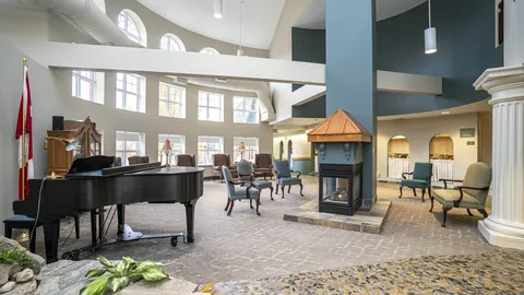 Grand piano and chairs around a fireplace in a high-ceilinged room