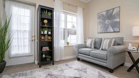 Sofa, bookshelf and side table beside a curtained window