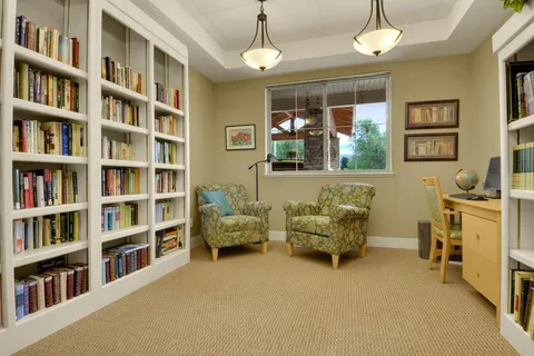 Library with two armchairs, bookshelves and a computer desk