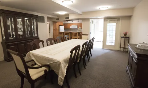 Dining room with a long table, wooden chairs and a kitchen counter