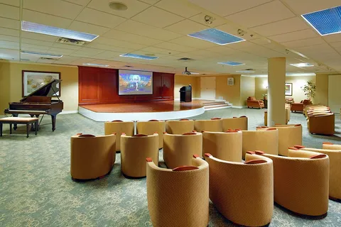 Screening room with rows of chairs, a piano and raised stage.