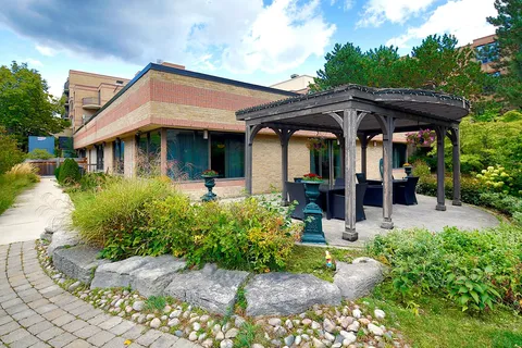 Low-rise residence beside a gazebo, paths and garden beds.