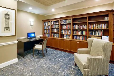 Library shelves beside a computer desk and lounge chair.