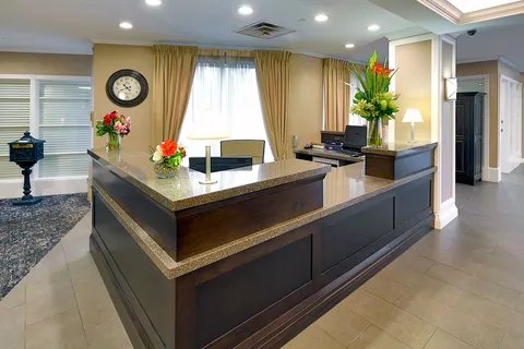 Reception desk with flowers beside a lobby window.