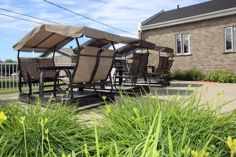 Patio with covered swings, planting beds and a stone-sided building
