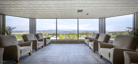 Armchairs arranged beside broad windows overlooking trees and hills
