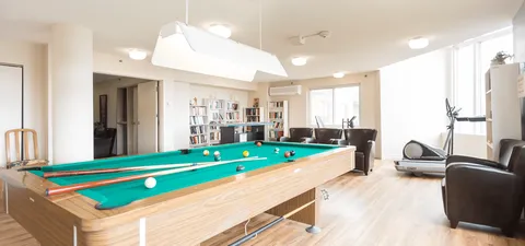 Billiard room with pool tables, chairs and large windows.