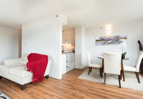 Living room with a sofa and dining table beside an open kitchen.