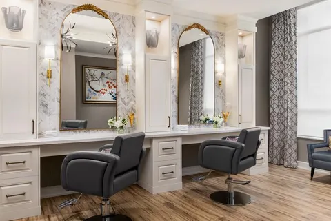 Salon styling chairs beside mirrors and white cabinets.