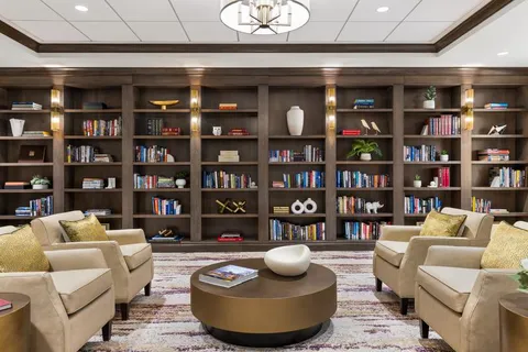 Library lounge with armchairs, coffee table and built-in bookshelves.