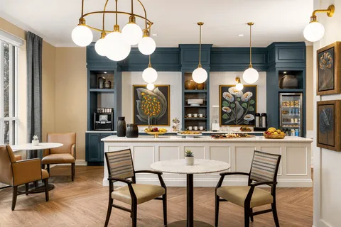 Bistro tables and chairs beside a blue counter and shelving.