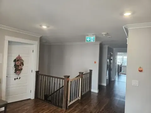 Hallway with wood flooring, a stair railing and white doors