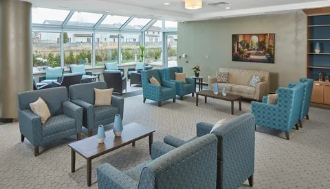 Sunroom with blue armchairs, sofas, low tables and large windows